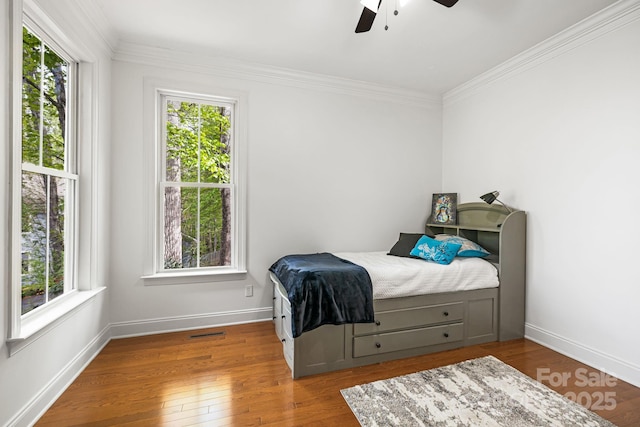 bedroom featuring multiple windows, ornamental molding, visible vents, and wood finished floors