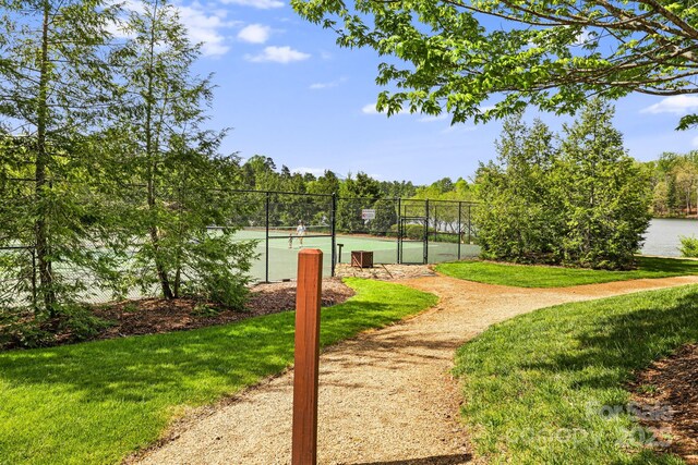 surrounding community with a yard, a tennis court, and fence