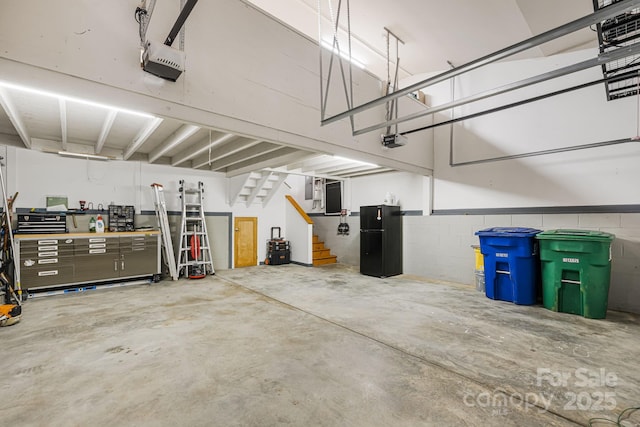 garage with concrete block wall, a garage door opener, and freestanding refrigerator