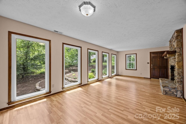 1128 Forest St, Mars Hill, NC 28754 - unfurnished living room featuring a textured ceiling, light wood finished floors, baseboards, and a stone fireplace