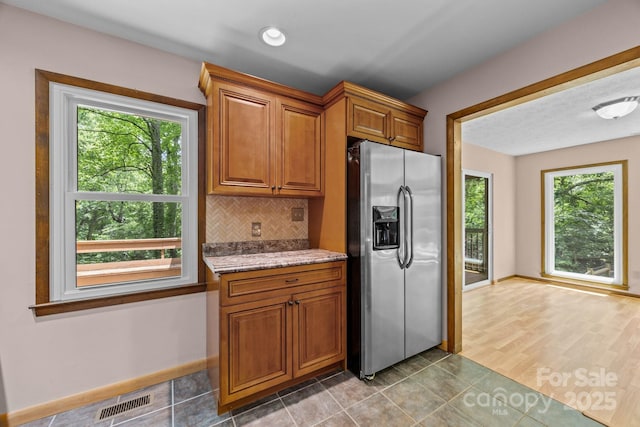 1128 Forest St, Mars Hill, NC 28754 - kitchen featuring stainless steel fridge with ice dispenser, backsplash, brown cabinets, light stone countertops, and baseboards