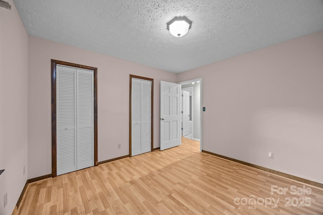 1128 Forest St, Mars Hill, NC 28754 - unfurnished bedroom featuring two closets, light wood finished floors, baseboards, and a textured ceiling