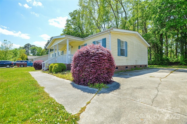 view of property exterior with a yard, driveway, a porch, and crawl space