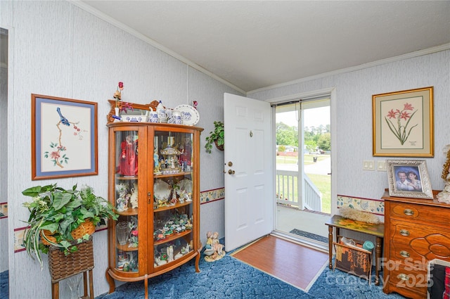 entryway with ornamental molding, wallpapered walls, and wood finished floors