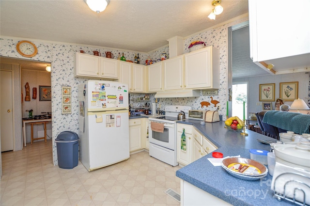 kitchen with wallpapered walls, dark countertops, white appliances, under cabinet range hood, and ornamental molding