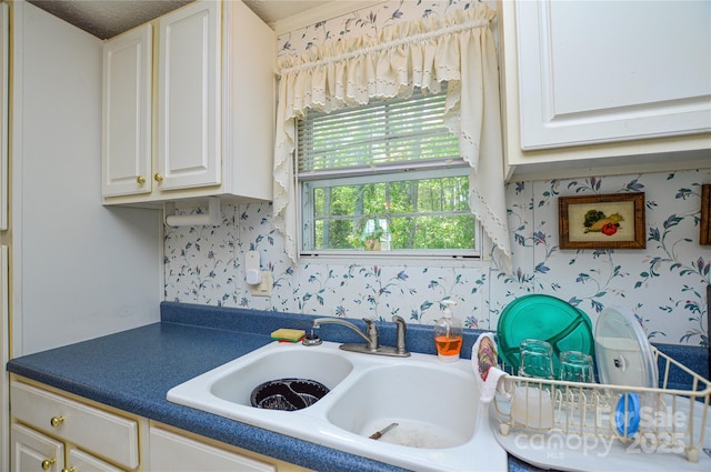 interior space with dark countertops, white cabinetry, wallpapered walls, and a sink