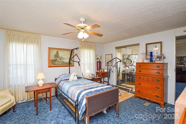 carpeted bedroom featuring ceiling fan, a closet, a textured ceiling, and ornamental molding