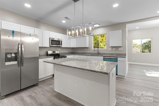 kitchen featuring visible vents, white cabinets, a sink, light wood-style flooring, and appliances with stainless steel finishes