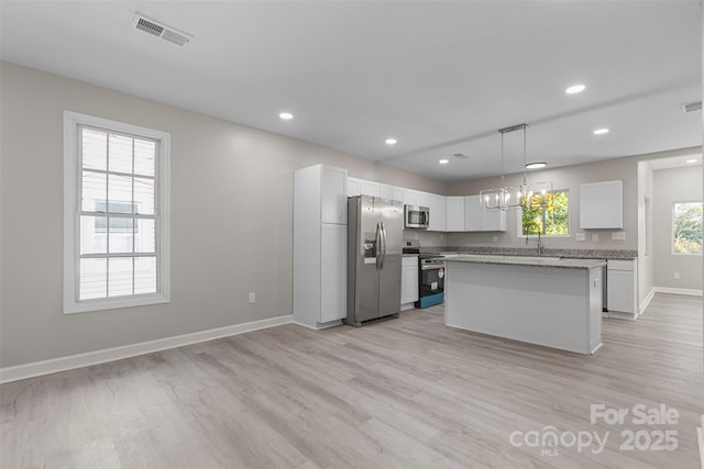 kitchen with white cabinets, stainless steel appliances, visible vents, and light wood-type flooring