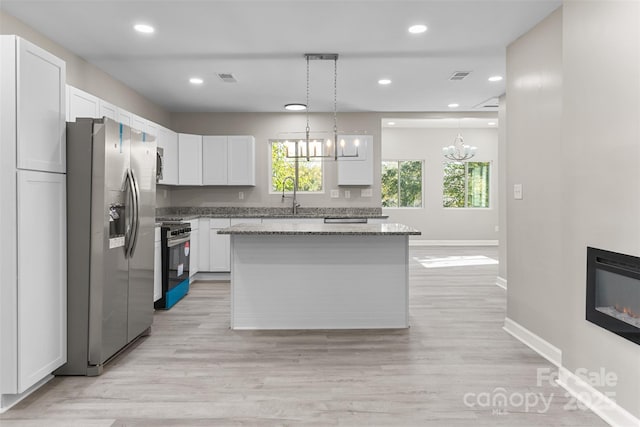 kitchen featuring white cabinets, a notable chandelier, stainless steel fridge, light stone counters, and electric stove