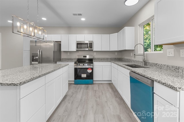 kitchen featuring a center island, a sink, light wood-style floors, stainless steel appliances, and white cabinetry