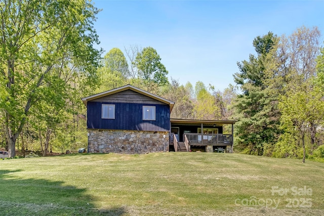 rear view of property featuring a yard, a wooden deck, and stone siding
