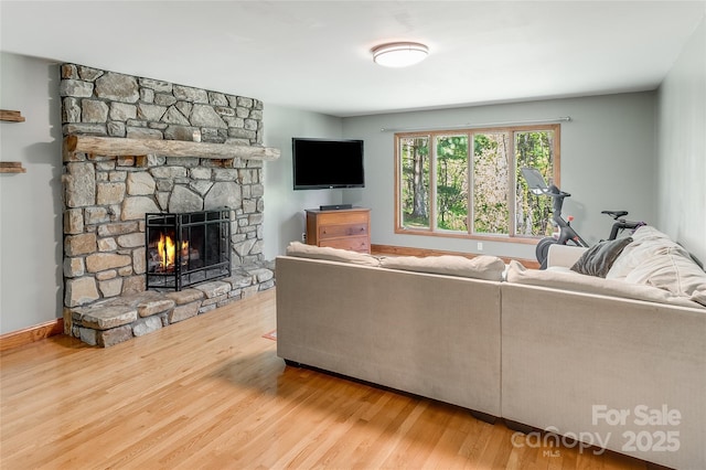 living room with a stone fireplace and wood finished floors