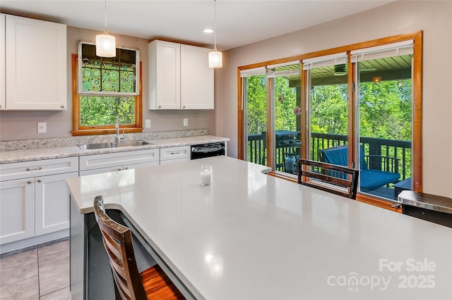 kitchen with a sink, light countertops, hanging light fixtures, and white cabinetry