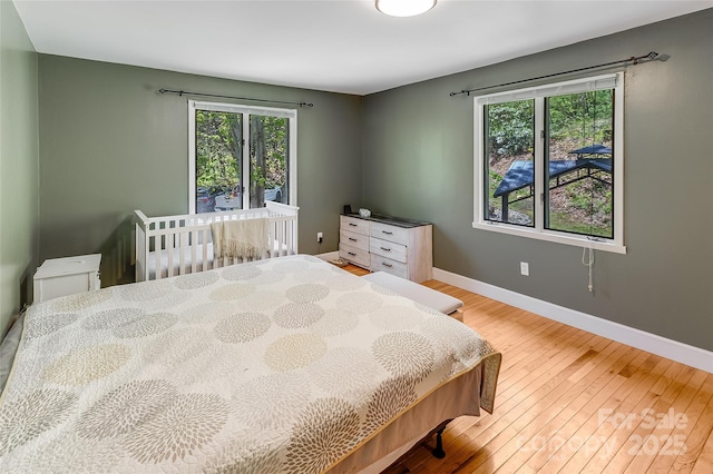bedroom with baseboards, multiple windows, and hardwood / wood-style floors