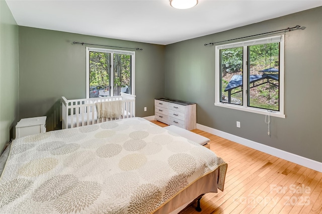 bedroom with baseboards, multiple windows, and hardwood / wood-style flooring
