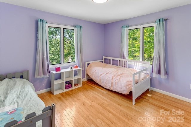 bedroom with wood-type flooring, baseboards, and multiple windows