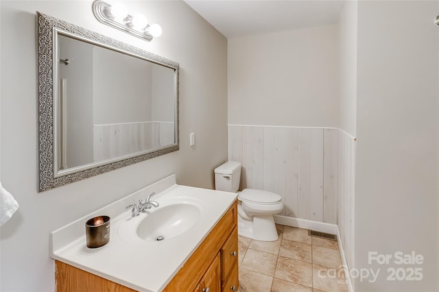 bathroom with vanity, visible vents, wainscoting, toilet, and wooden walls