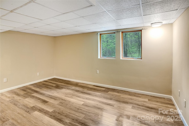 spare room featuring baseboards, wood finished floors, and a paneled ceiling