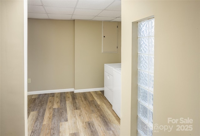 washroom with electric panel, laundry area, washing machine and clothes dryer, wood finished floors, and baseboards