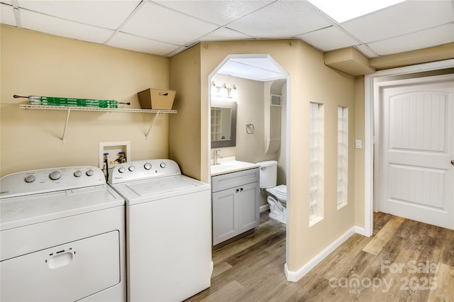 laundry room with separate washer and dryer, laundry area, arched walkways, and light wood-style flooring