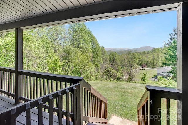 view of yard with a view of trees and a deck with mountain view
