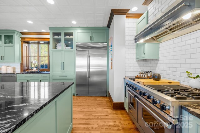12613B Oak Grove Rd, Stanfield, NC 28163 - kitchen featuring green cabinetry, high end appliances, wall chimney exhaust hood, recessed lighting, and tasteful backsplash