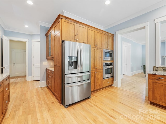 3825 Mountain Cove Dr, Charlotte, NC 28216 - kitchen with stainless steel appliances, crown molding, brown cabinetry, light wood-type flooring, and light stone counters
