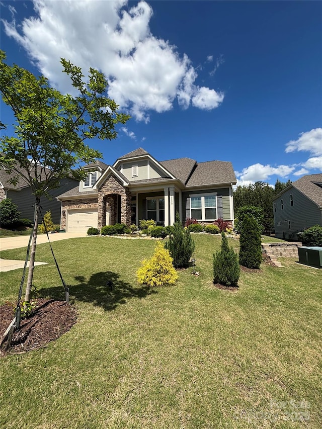 craftsman-style home with concrete driveway, a garage, a front lawn, and stone siding