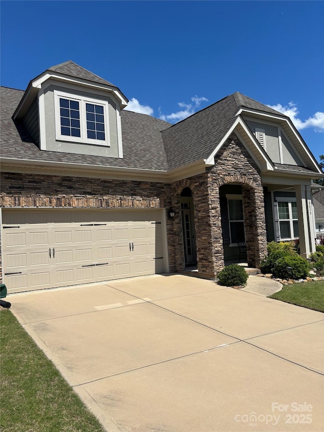 view of front facade featuring stone siding, stucco siding, driveway, and roof with shingles