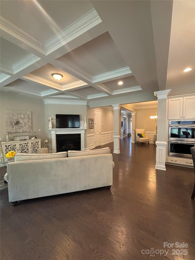 living area with decorative columns, a fireplace, crown molding, beamed ceiling, and dark wood-style floors