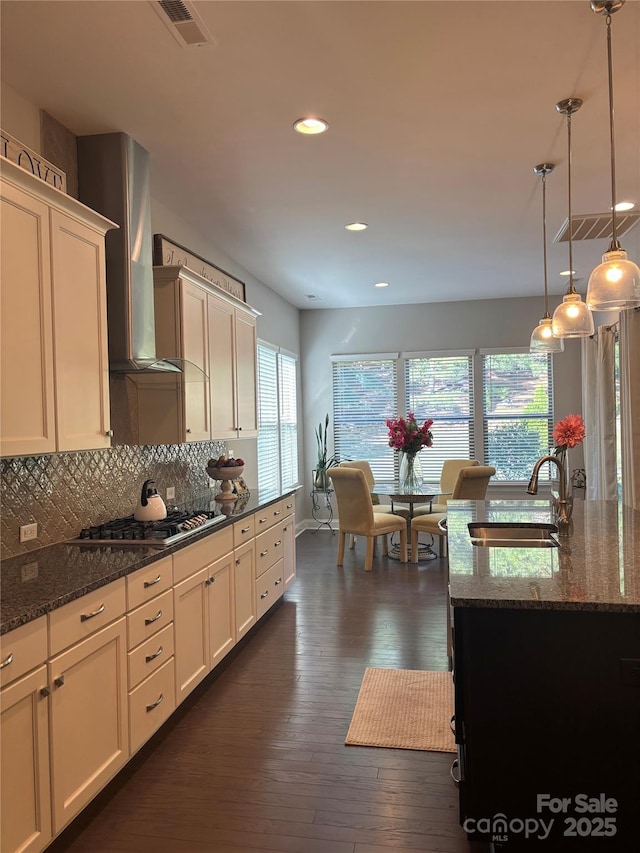kitchen with a sink, tasteful backsplash, stainless steel gas stovetop, visible vents, and wall chimney exhaust hood