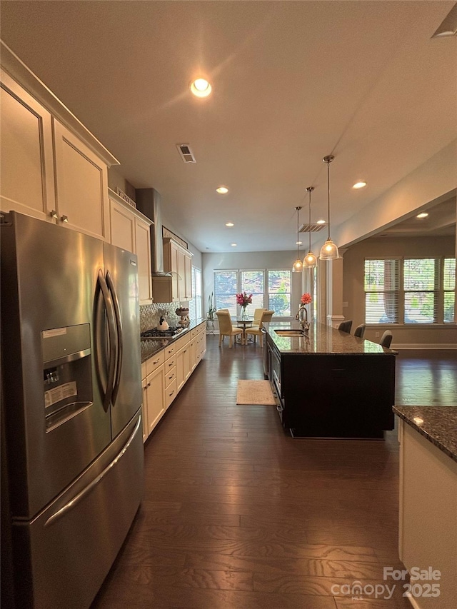 kitchen with recessed lighting, visible vents, dark stone countertops, wall chimney exhaust hood, and stainless steel appliances