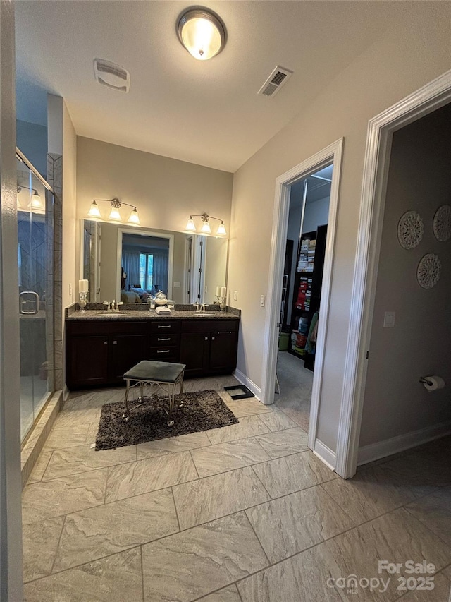 full bathroom featuring a stall shower, baseboards, visible vents, a sink, and double vanity