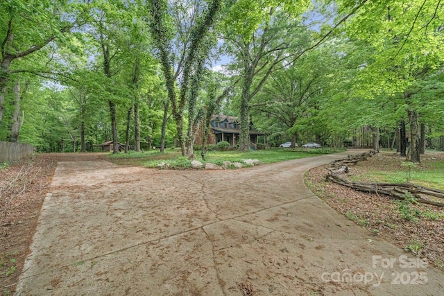 surrounding community featuring driveway and a view of trees