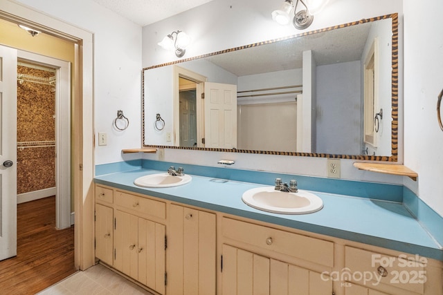 full bath with a textured ceiling, double vanity, and a sink