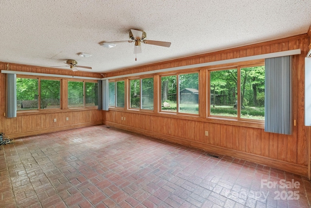 unfurnished sunroom with wooden walls, brick floor, and baseboards