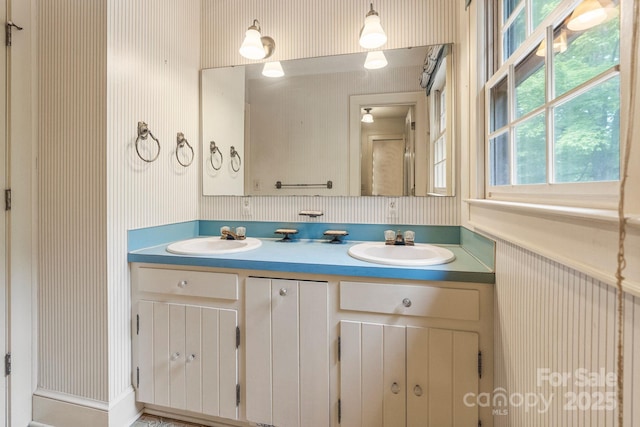 full bath with wallpapered walls, a sink, and double vanity