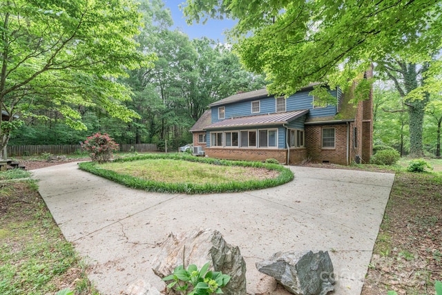 view of front of home featuring concrete driveway, brick siding, and fence