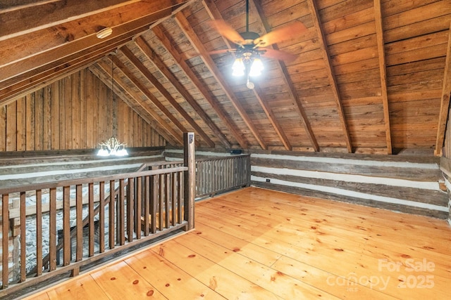 additional living space with lofted ceiling, hardwood / wood-style floors, a ceiling fan, and wooden walls
