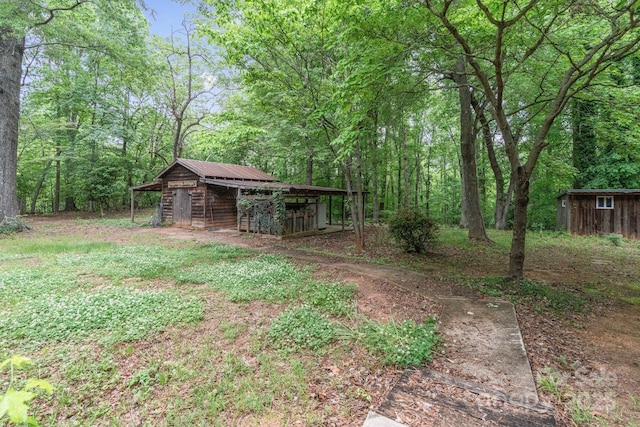 view of yard with a wooded view and an outdoor structure