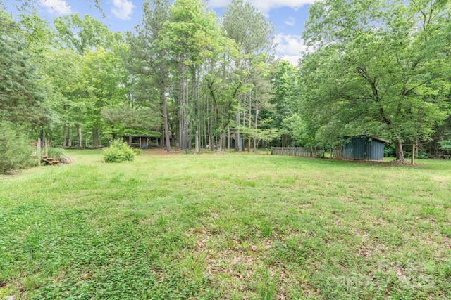 view of yard with an outdoor structure and a view of trees