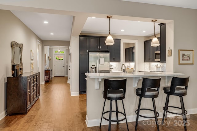 75 Balsam High Rd, Biltmore Lake, NC 28715 - kitchen with stainless steel appliances, a breakfast bar area, a peninsula, decorative backsplash, and light countertops