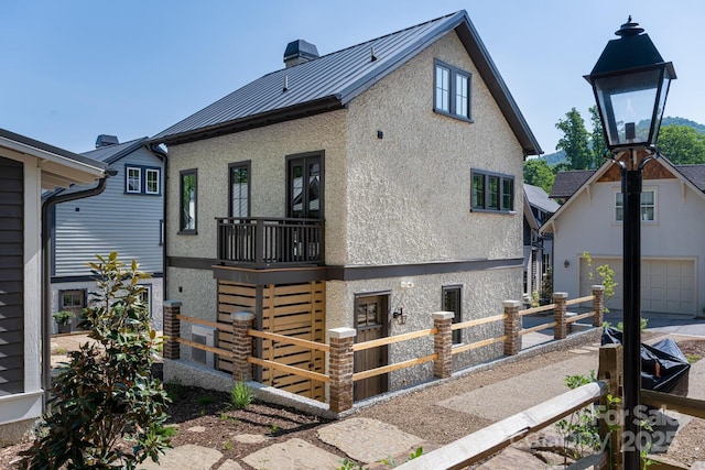 exterior space featuring a standing seam roof, stucco siding, a garage, and fence private yard