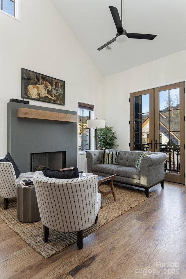 living room featuring french doors, a fireplace, high vaulted ceiling, and wood finished floors