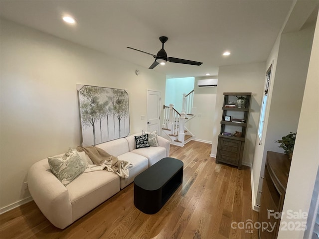living area with a wall mounted air conditioner, wood finished floors, recessed lighting, stairway, and ceiling fan