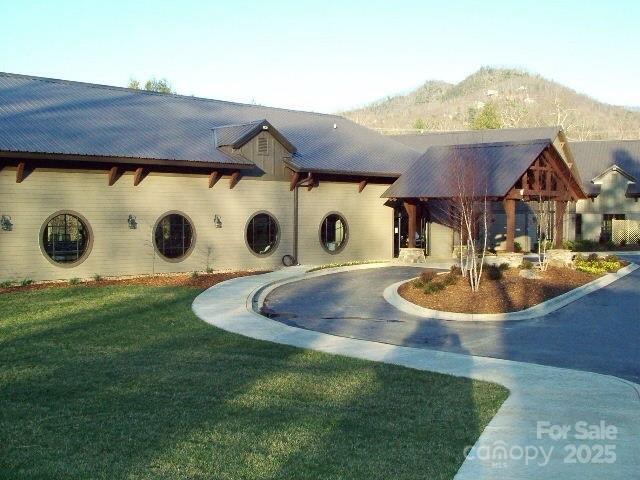 exterior space with curved driveway, a mountain view, and a lawn