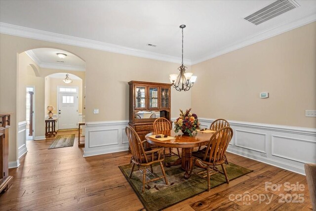 1409 Tupelo Rd, Clover, SC 29710 - dining space with arched walkways, ornamental molding, dark wood finished floors, a chandelier, and a wainscoted wall