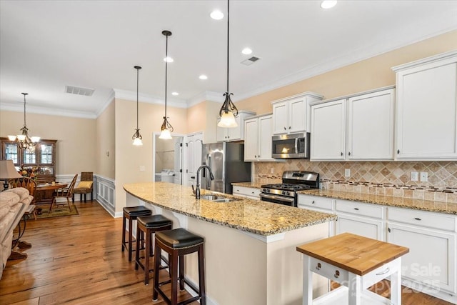 1409 Tupelo Rd, Clover, SC 29710 - kitchen with appliances with stainless steel finishes, backsplash, a kitchen island with sink, white cabinetry, and crown molding