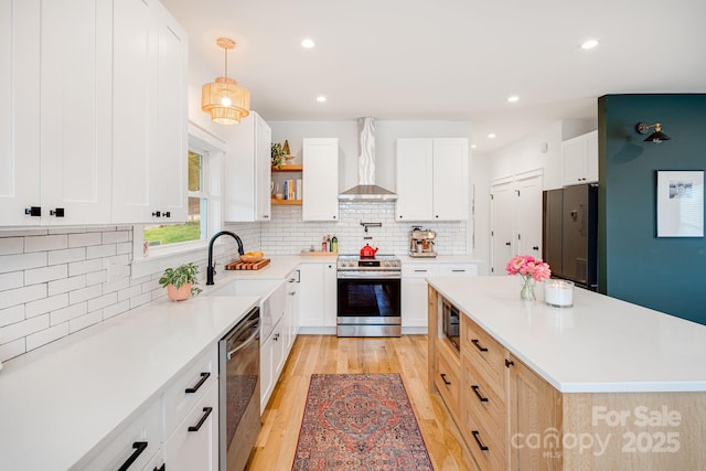 304 Magnolia Ridge Rd, Swannanoa, NC 28778 - kitchen featuring appliances with stainless steel finishes, wall chimney exhaust hood, light wood-type flooring, a kitchen island, and light countertops